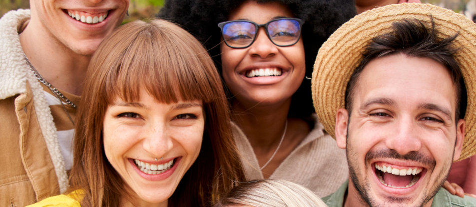 A group of six people smiling and looking at the camera, standing closely together in an outdoor setting.