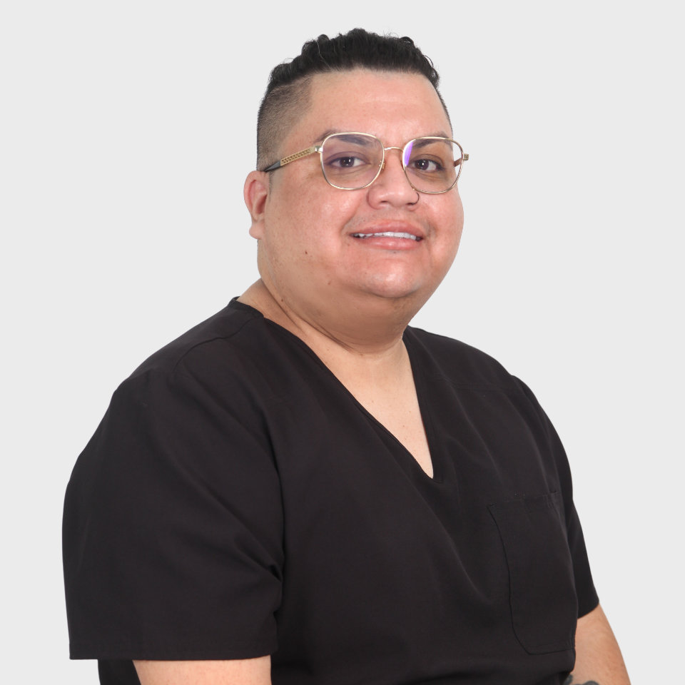 Person wearing glasses and a black shirt, smiling, against a plain background.